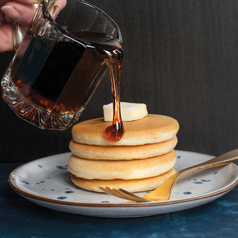 Golden maple syrup pouring onto stack of mini silver dollar pancakes from Nordic Ware pancake pan