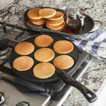 Nordic Ware silver dollar pancake pan with golden mini pancakes cooking, stack of finished pancakes on plate