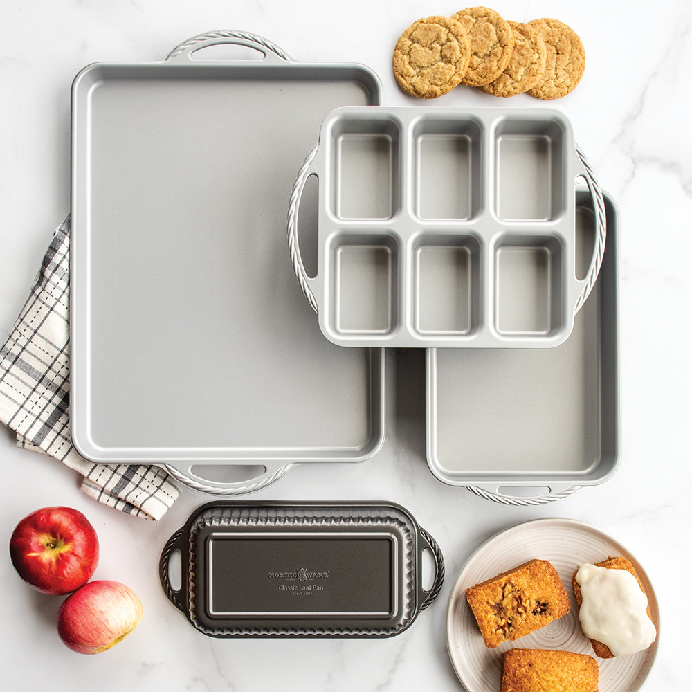 Nordic Ware aluminum ProCast baking pans with baked autumn treats including muffins, cookies, and bread loaves