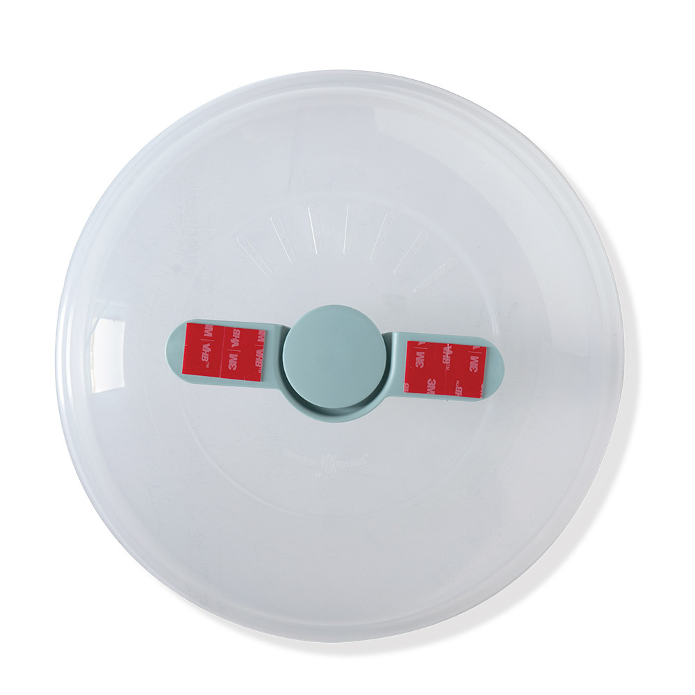 Nordic Ware Up & Away spatter cover with red protective tape strip, overhead view showing compact design