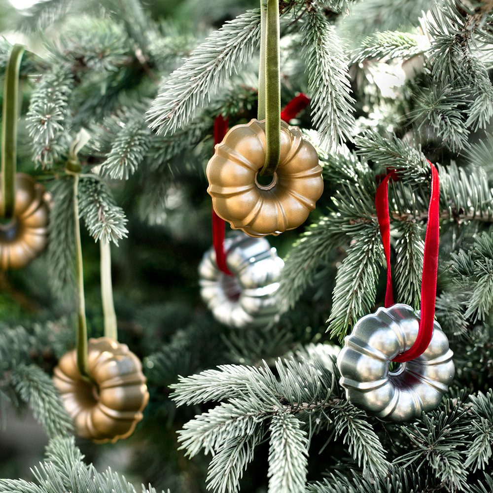 Two silver cast aluminum Nordic Ware miniature bundt ornaments hanging on Christmas tree branches