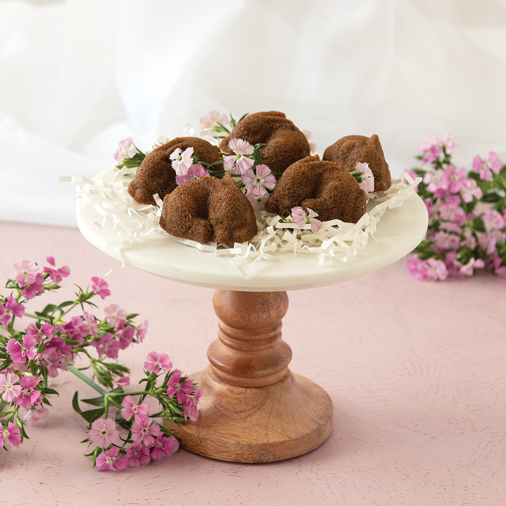 Six chocolate bunny-shaped cakelets baked in Nordic Ware aluminum Baby Bunny Bites pan, showing detailed ears and faces