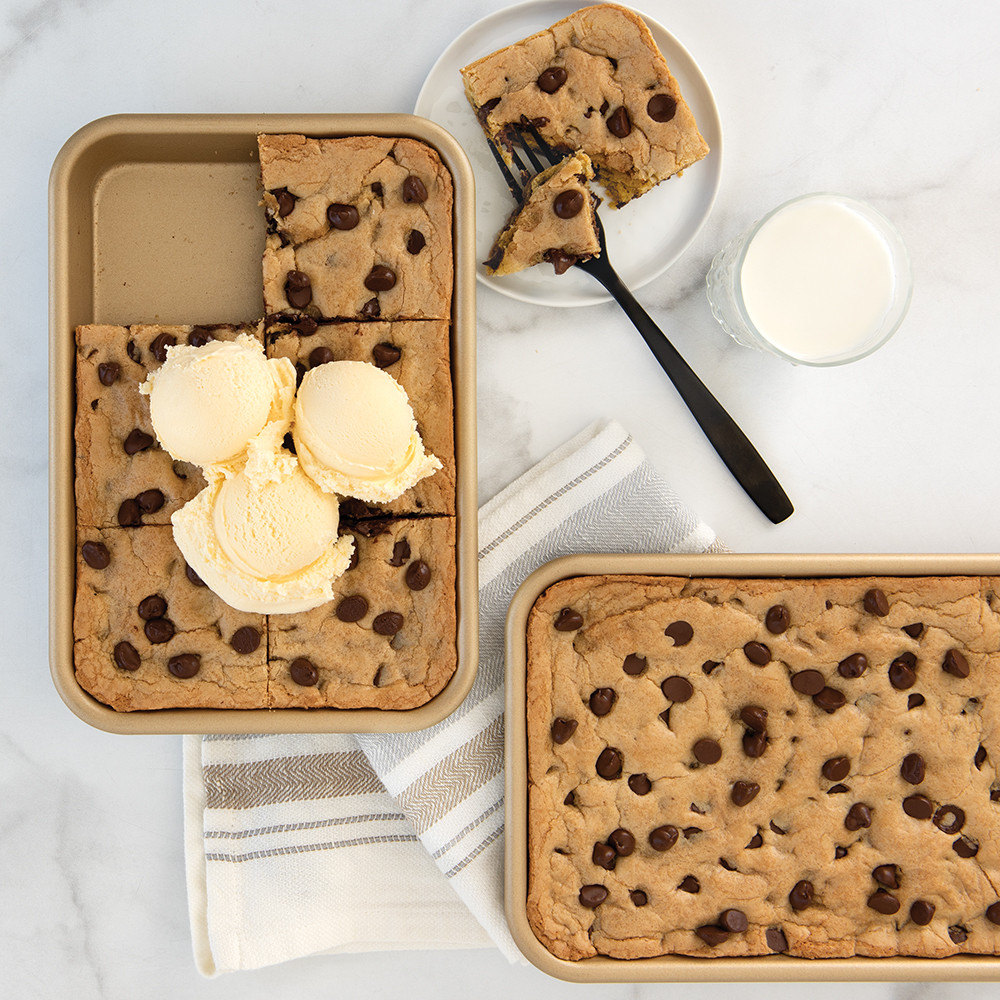 Small rectangular Nordic Ware nonstick baking sheet with golden sheet pan cookie, one slice cut and topped with vanilla ice cream