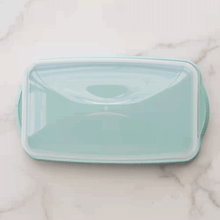 Golden braided loaf cake displayed on Nordic Ware aluminum loaf keeper with vented lid