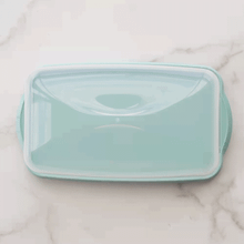 Golden braided loaf cake displayed on Nordic Ware aluminum loaf keeper with vented lid