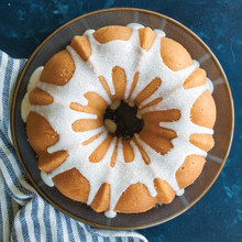 Golden glazed bundt cake on white serving plate, baked in fluted bundt pan showing detailed ridged pattern