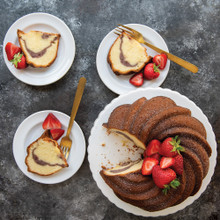 Sliced bundt cake with swirled pattern from Nordic Ware Swirl Bundt pan, dusted with powdered sugar and topped with fresh strawberries
