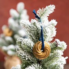 Nordic Ware gold-colored Heritage Bundt pan ornament hanging on white Christmas tree branch