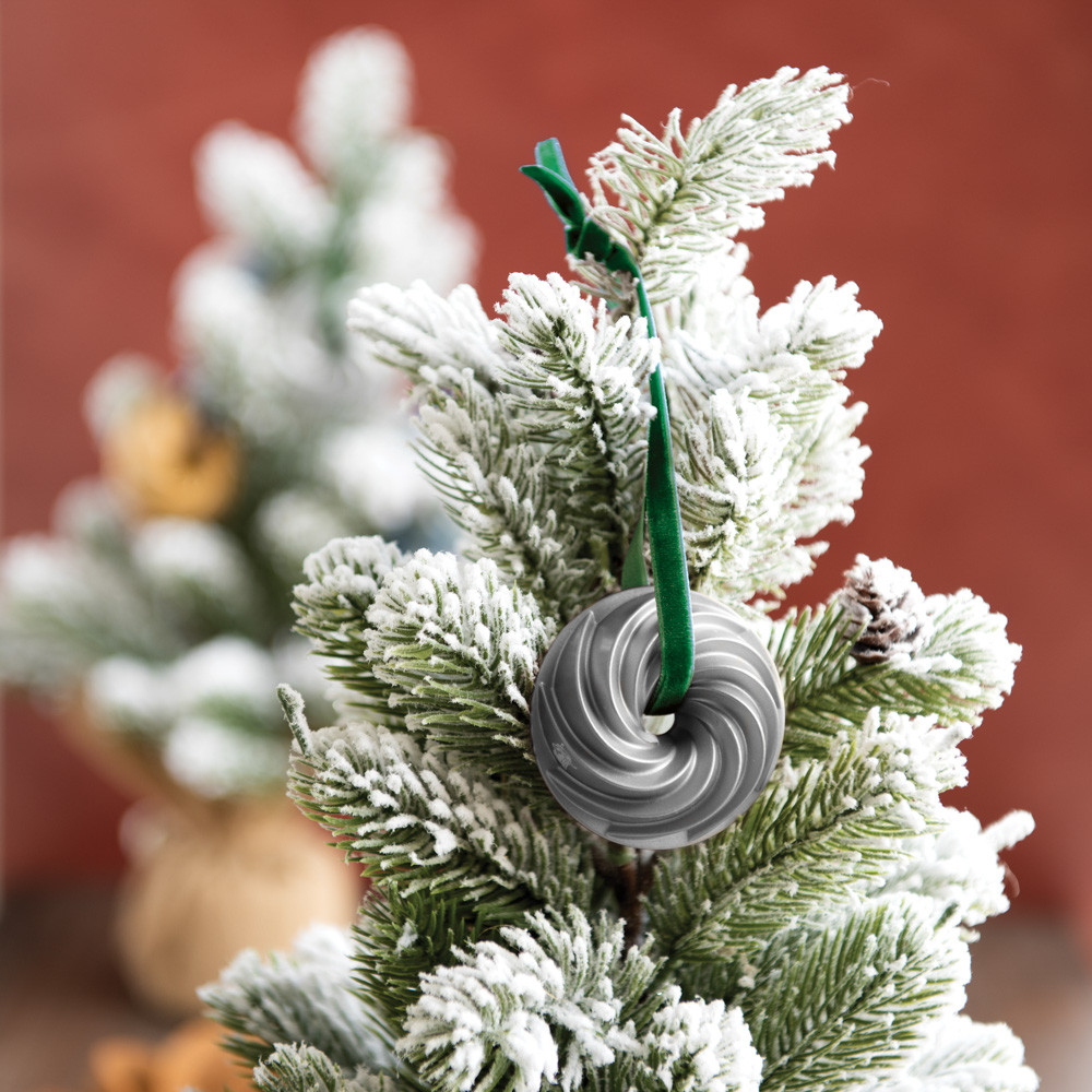 Nordic Ware silver-colored Heritage Bundt pan ornament hanging on white Christmas tree branch