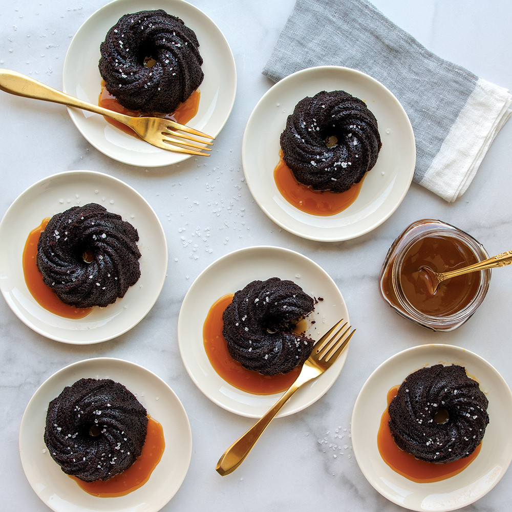 Six chocolate bundtlette cakes with decorative swirl pattern, baked in Nordic Ware aluminum pan, plated and ready to serve