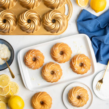 Six glaced bundtlettes on white plage baked in Nordic Ware Swirl Bundtlette aluminum pan