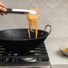 Nordic Ware 14-inch black non-stick wok with stir-fried vegetables and meat, showing colorful peppers and broccoli