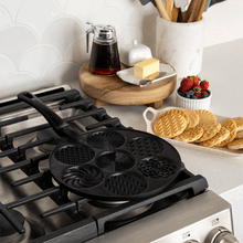 Nordic Ware aluminum pancake pan with seven round wells cooking golden pancakes on stovetop