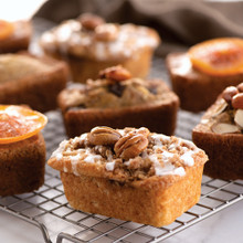 Six golden mini loaf cakes cooling on wire rack, baked in Nordic Ware ProCast aluminum mini loaf pan
