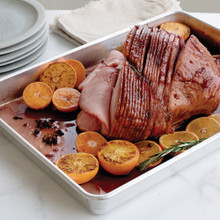 Nordic Ware aluminum big batch pan with golden-brown glazed ham, rectangular shape with raised edges