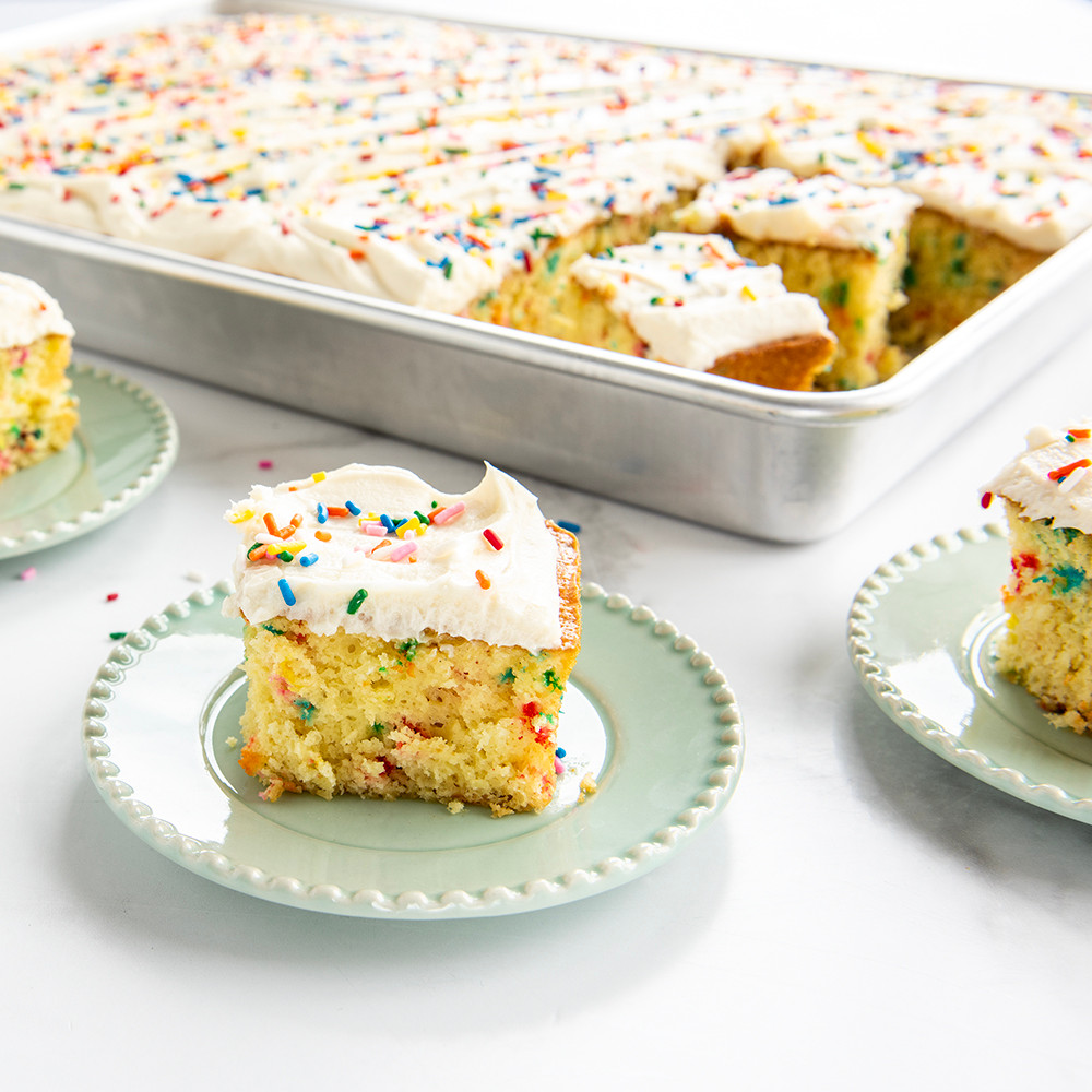 Nordic Ware Naturals aluminum big batch pan with golden sheet cake, three square pieces plated beside