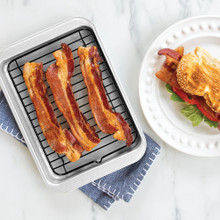 Nordic Ware aluminum 2-piece broiler set with cooked bacon strips on wire rack over baking sheet