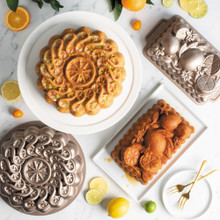 Nordic Ware citrus-themed aluminum baking collection with twist cake pan, loaf pan, displaying baked citrus cake
