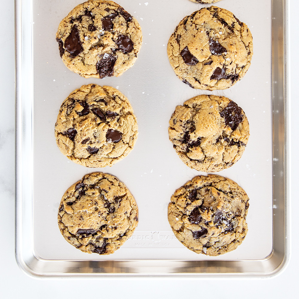 Freshly baked chocolate chip cookies arranged on Nordic Ware aluminum half sheet pan with natural finish