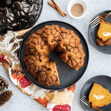 Sliced pumpkin-shaped bundt cake on white plate with Nordic Ware Pumpkin Patch bundt pan in background
