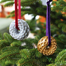 Two Nordic Ware collectible cast metal Jubilee Bundt ornaments in gold and silver finishes hanging on Christmas tree