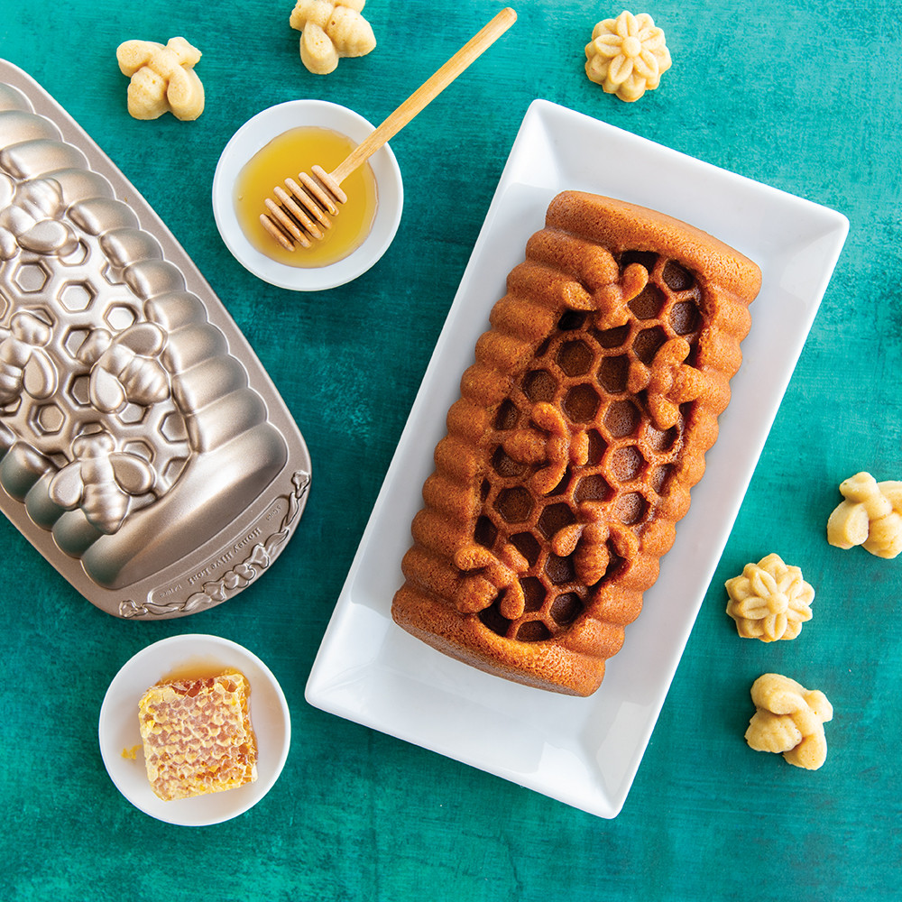 Golden honey-glazed loaf cake in Nordic Ware Honey Hive aluminum pan showing hexagonal honeycomb pattern detail