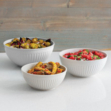 White Nordic Ware mixing bowls filled with fresh salad and fruit arranged on outdoor picnic table
