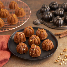 Nordic Ware aluminum Lil' Pumpkin Cakelets pan with six baked pumpkin-shaped cakes, caramel drizzle and chopped nuts
