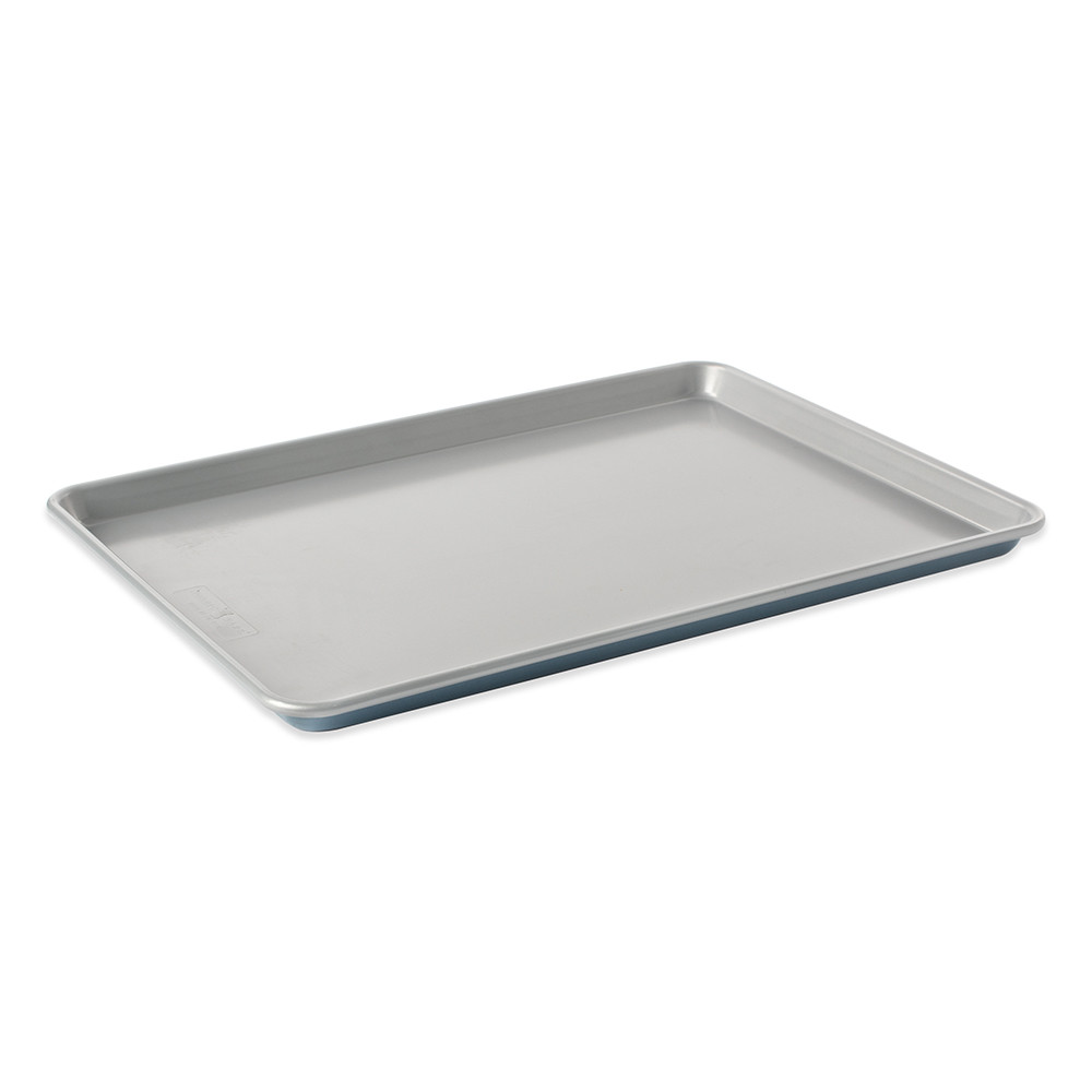 Nordic Ware aluminum sheet pan with raised edges, natural silver finish, angled view showing rectangular shape