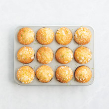 Nordic Ware aluminum muffin pan with 12 golden lemon poppy seed muffins, natural silver finish