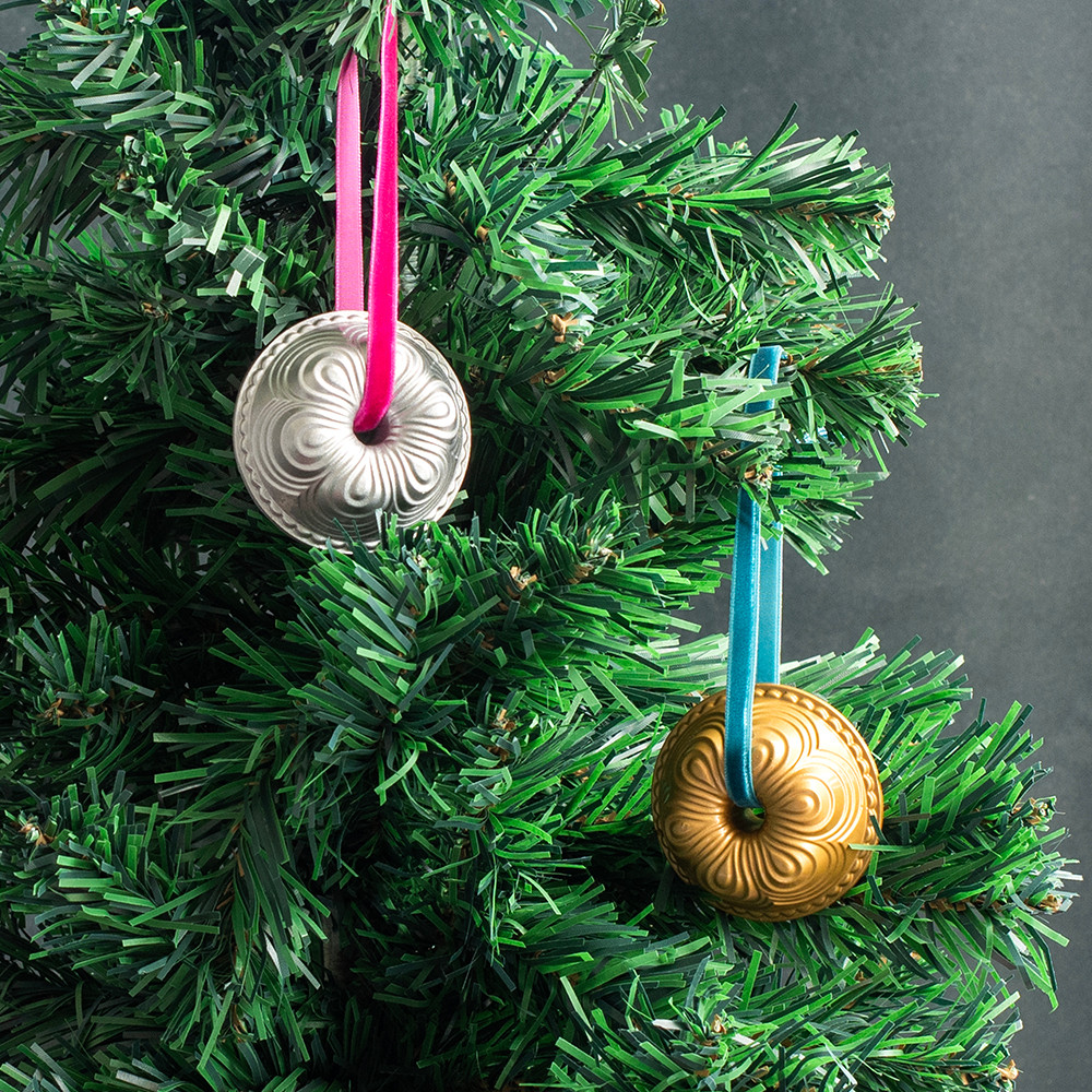 Two Nordic Ware miniature cast aluminum Chiffon Bundt ornaments in silver and gold finishes hanging on Christmas tree