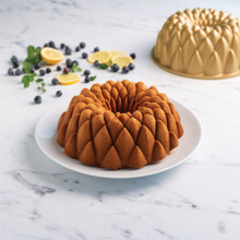 Nordic Ware Kaleidoscope bundt pan with golden baked cake, fresh blueberries and lemon slices arranged around