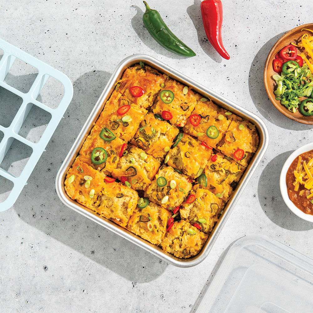 Nordic Ware aluminum brownie pan with baked taco casserole cut into 16 square portions, golden brown surface