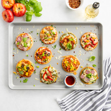 Two rectangular flatbreads with meat and vegetables baked on Nordic Ware nonstick half sheet pan, golden brown