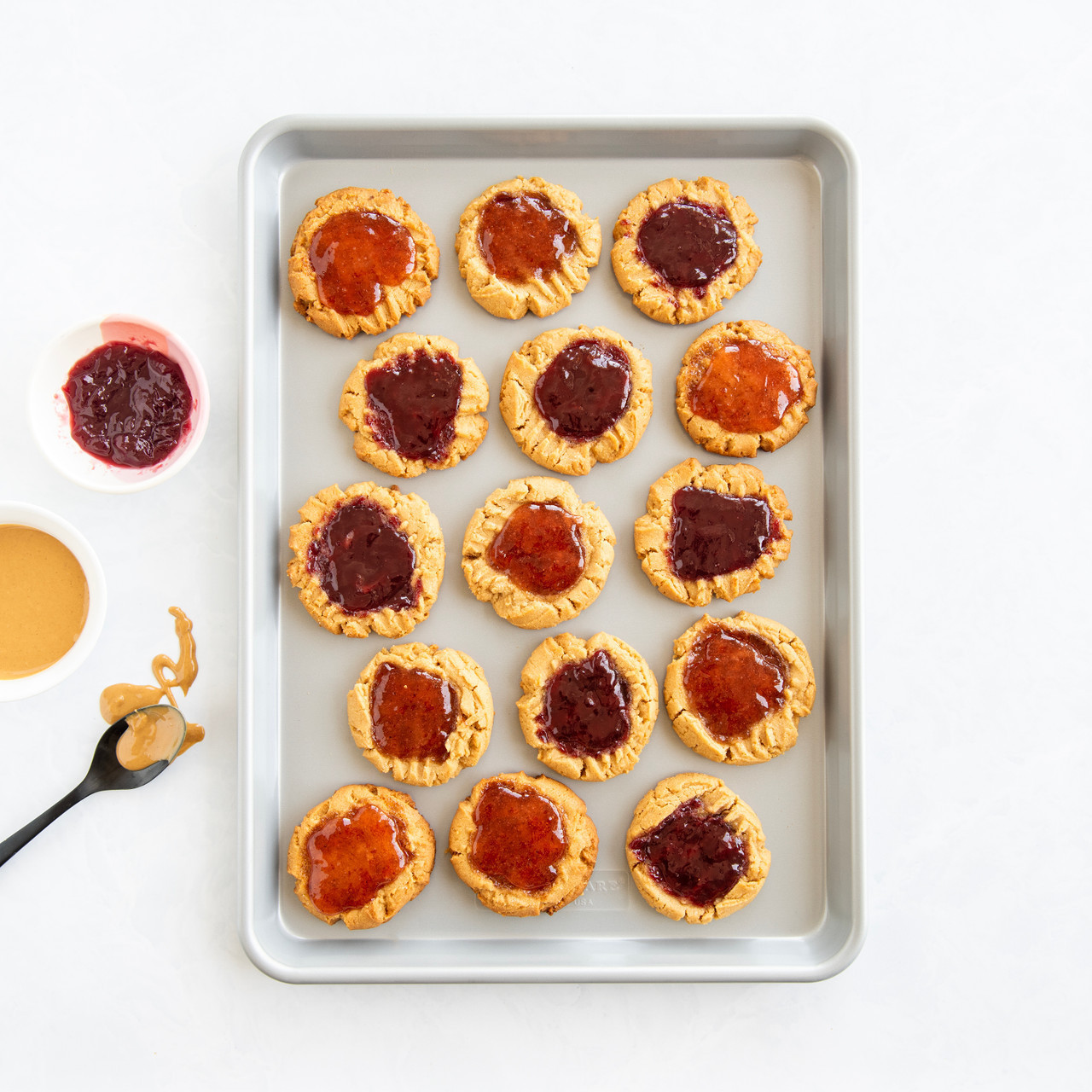 Nordic Ware nonstick half sheet pan with golden-brown peanut butter cookies topped with jam dollops