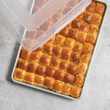 Nordic Ware aluminum rectangular baking pan with lid, containing freshly baked golden dinner rolls