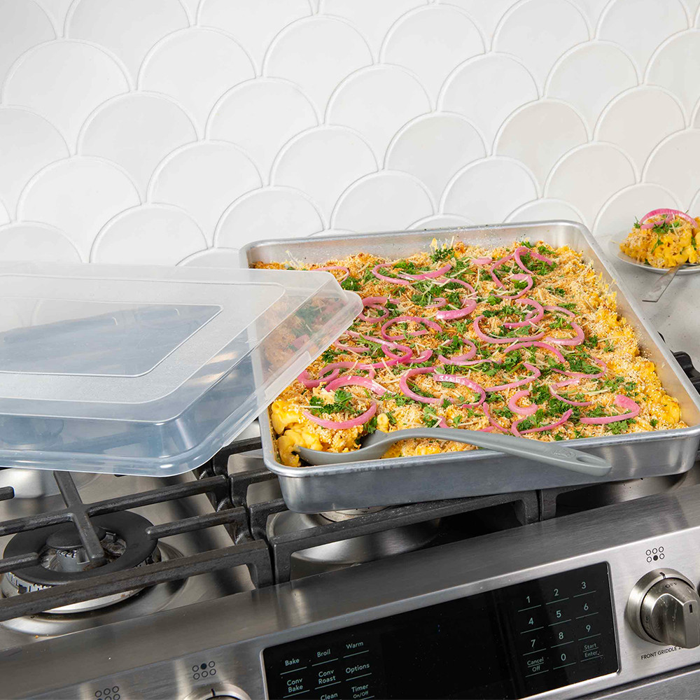 Nordic Ware aluminum big batch pan with lid on stovetop, filled with creamy baked mac and cheese