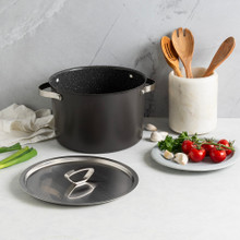 Nordic Ware Verde green ceramic 8-quart stock pot with lid, styled with fresh tomatoes and wooden utensils