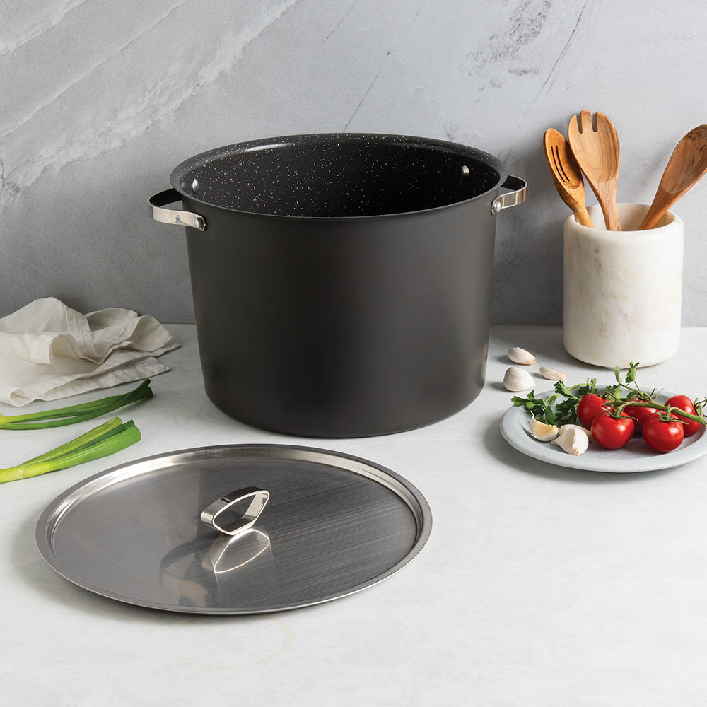 Nordic Ware Verde 20-quart green stock pot with lid, surrounded by fresh cherry tomatoes and wooden utensils