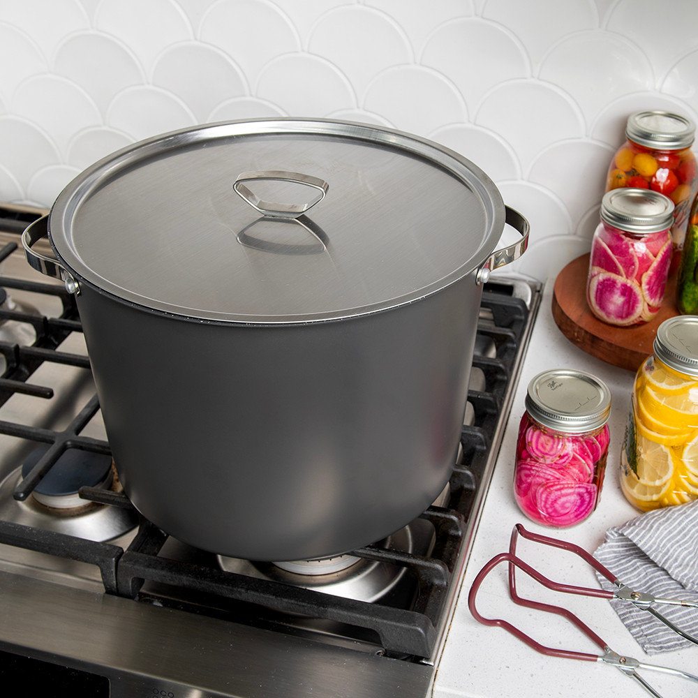 20 Qt Stock Pot with closed lid on stovetop displayed with various jars of vegetables 
