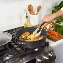 Green Nordic Ware braiser pan cooking chicken with vegetables on stovetop, lid being lifted to show contents