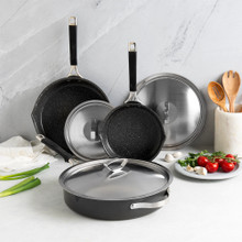 Nordic Ware Verde ceramic nonstick skillets in three sizes with glass lids, displayed with fresh vegetables and herbs