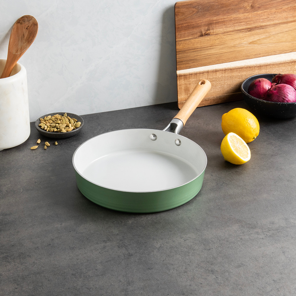 Nordic Ware ceramic nonstick 10-inch skillet in cardamom color on countertop with cooking ingredients and utensils