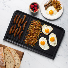 Nordic Ware Basalt dual-zone grill griddle with cooked sausages, eggs, and hash browns alongside fresh berries and bread