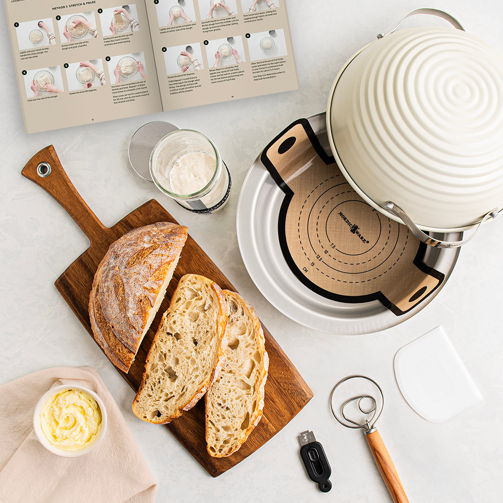 Nordic Ware 9-piece sourdough bread baking kit with sliced artisan bread, aluminum loaf pan, and baking accessories on white surface