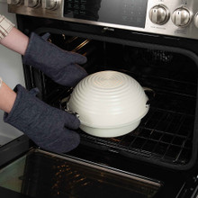 Nordic Ware covered aluminum loaf pan being placed into oven, showing silver finish and ergonomic handles