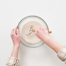 Nordic Ware Danish whisk mixing sourdough dough in clear glass bowl, hands kneading sticky bread mixture