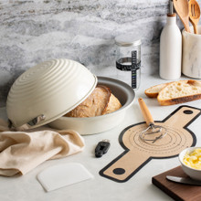 Nordic Ware 9-piece sourdough bread baking kit with baked artisan bread, aluminum loaf pan, and baking accessories in marble kitchen background