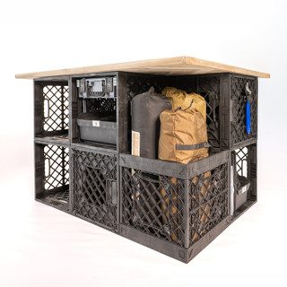 Angled view of a CrateShot Bench with open UbeCube crate storage, loose field gear, and a wood tabletop.