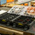 UbeCube (modular-storage-crate) BaseBox (hardware-organizer-box) units open on a workshop table showing labeled compartments filled with connectors, hardware, and organized small parts.